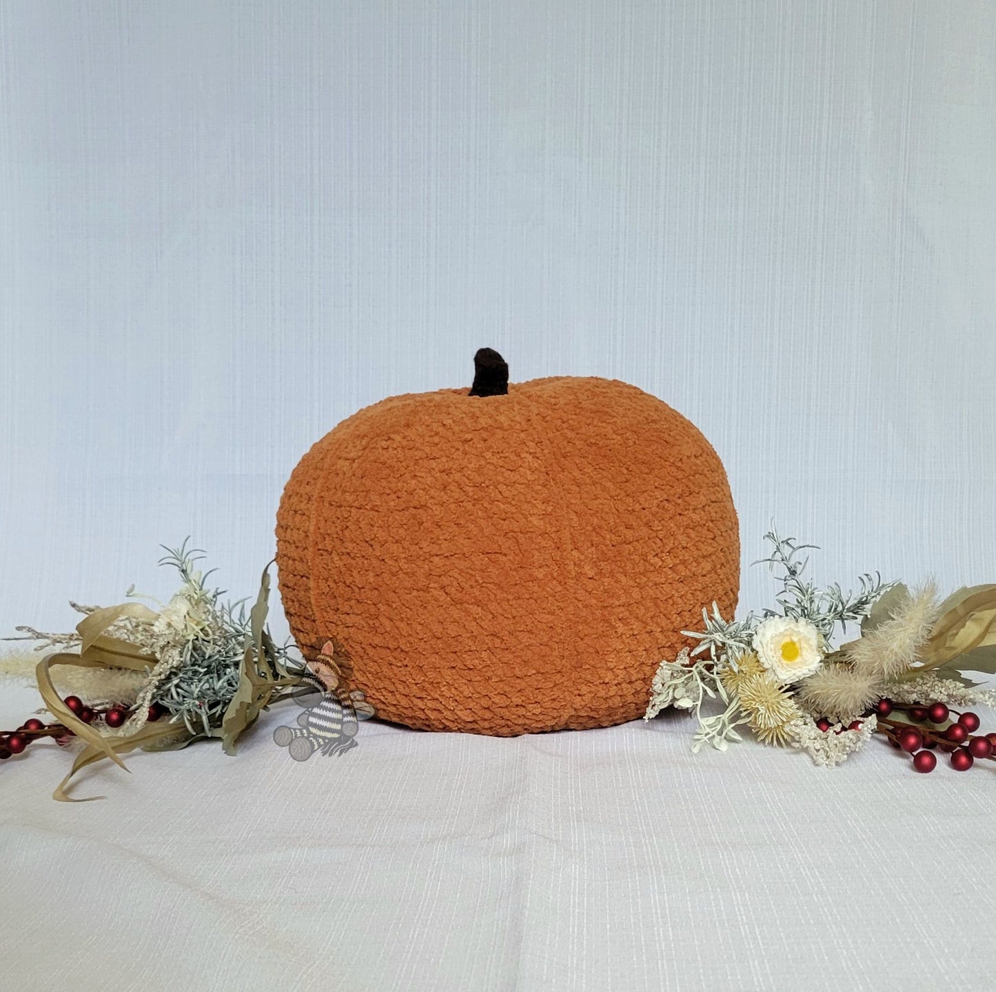 large crocheted pumpkin decoration with floral and berry arrangement on a light background