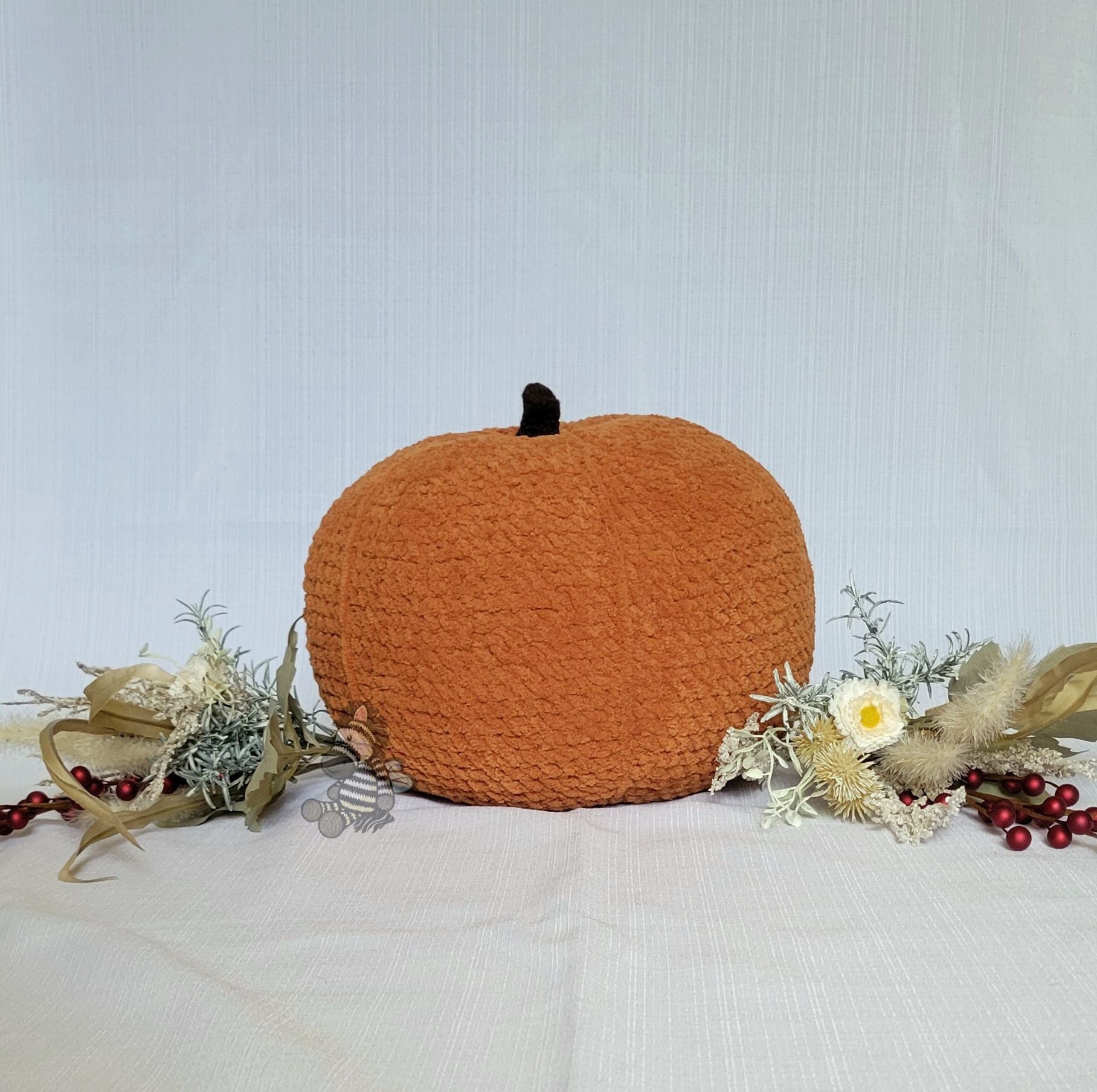 large crocheted pumpkin decoration with floral and berry arrangement on a light background