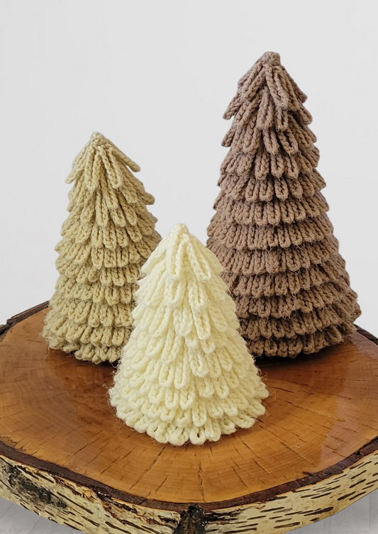 Three crocheted Christmas trees in beige, tan, and cream on a wooden base.