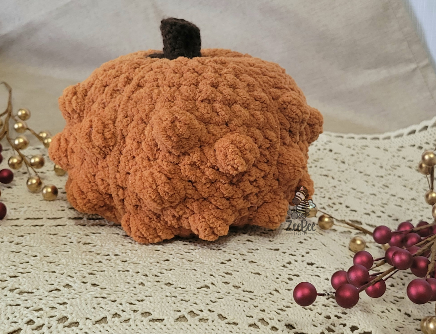 Textured, polka dot solid orange pumpkin decoration on a lace tablecloth with decorative elements.