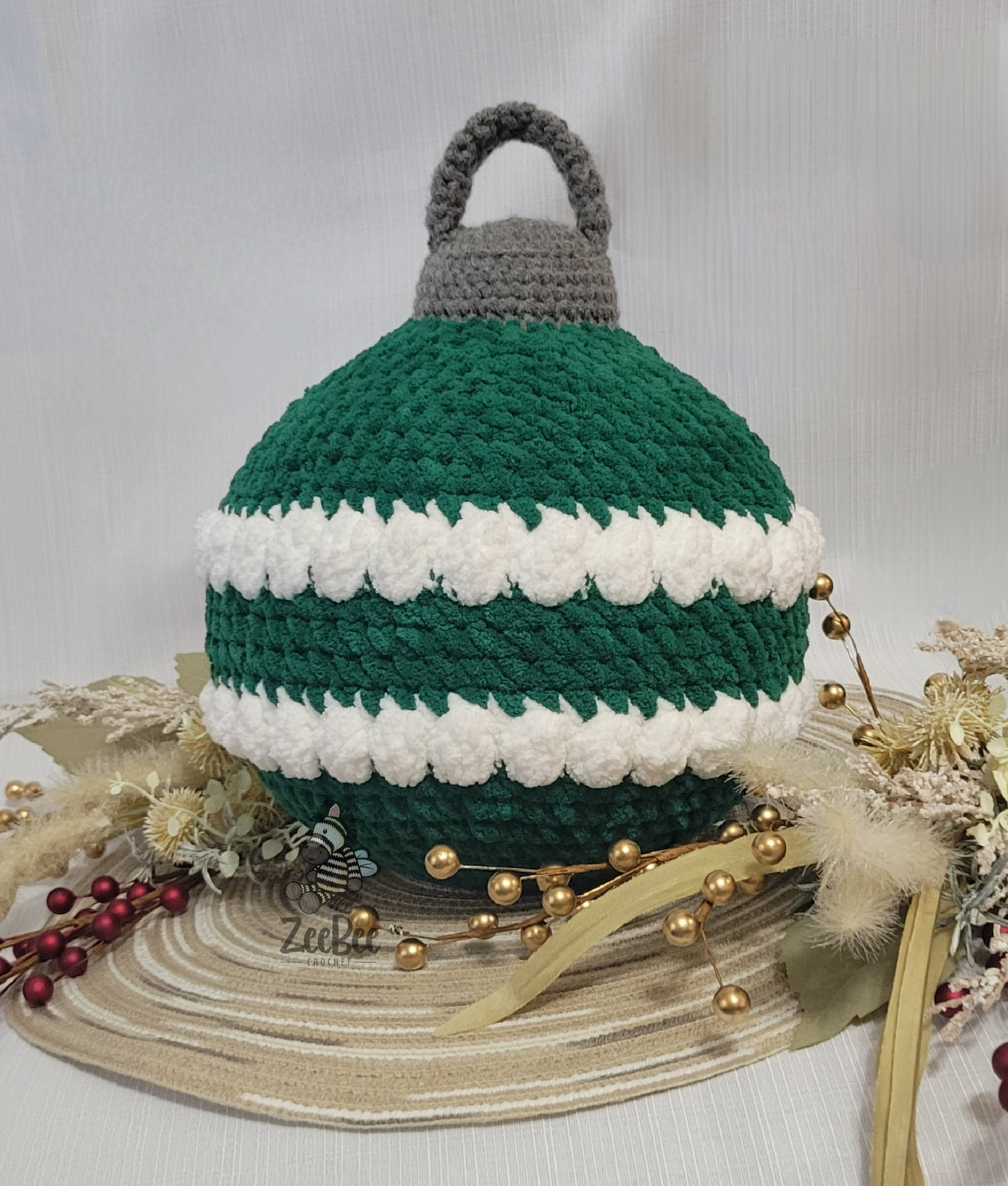 Crocheted ornament pillow with green, white stripes, and gray colors on a decorative surface.