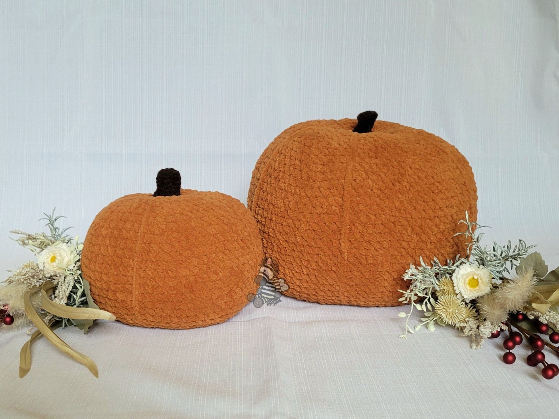 Two crocheted pumpkins on a light background with decorative elements.