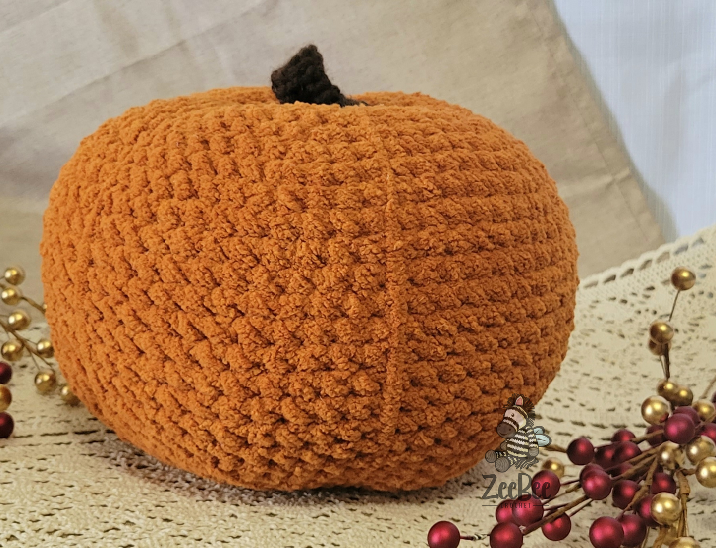 Small simple crocheted pumpkin decoration on a textured surface with decorative elements.