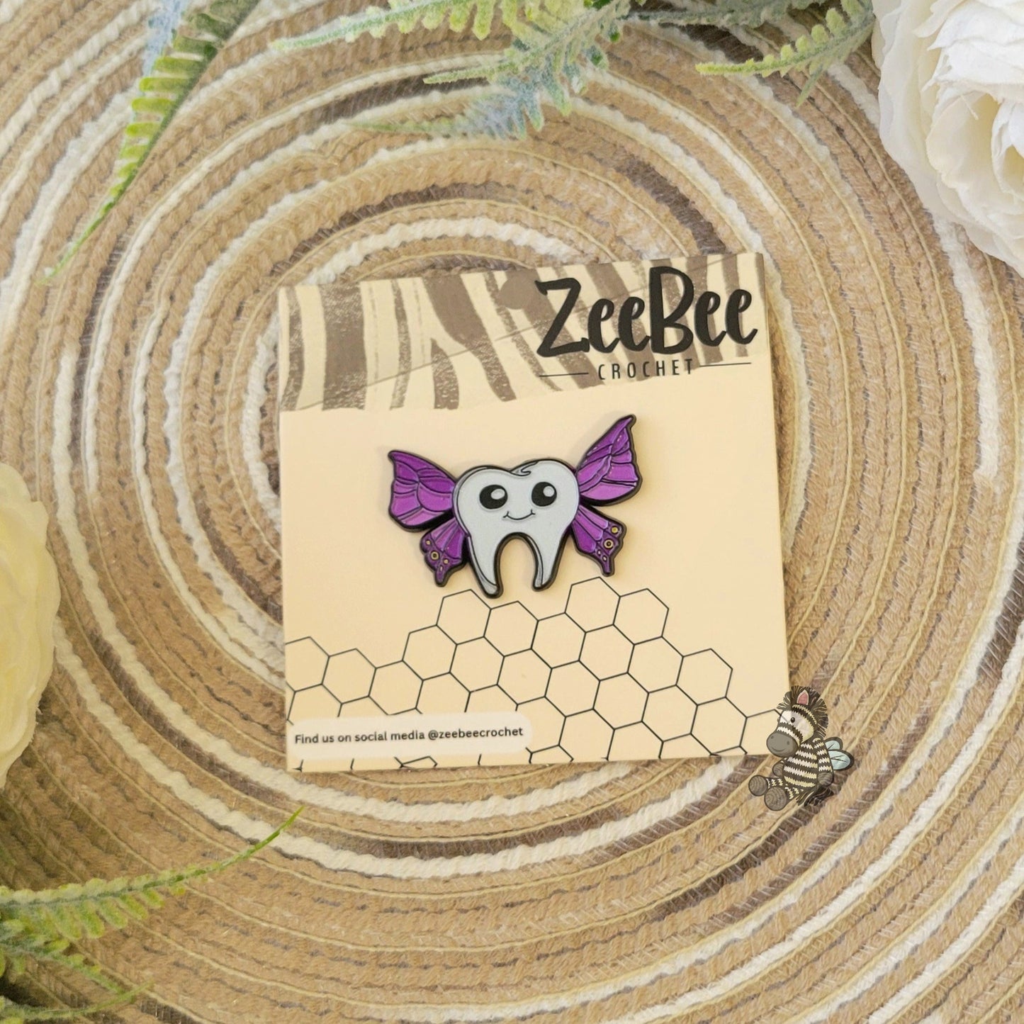 ZeeBee Crochet official tooth-fairy pin with purple wings on a wooden surface