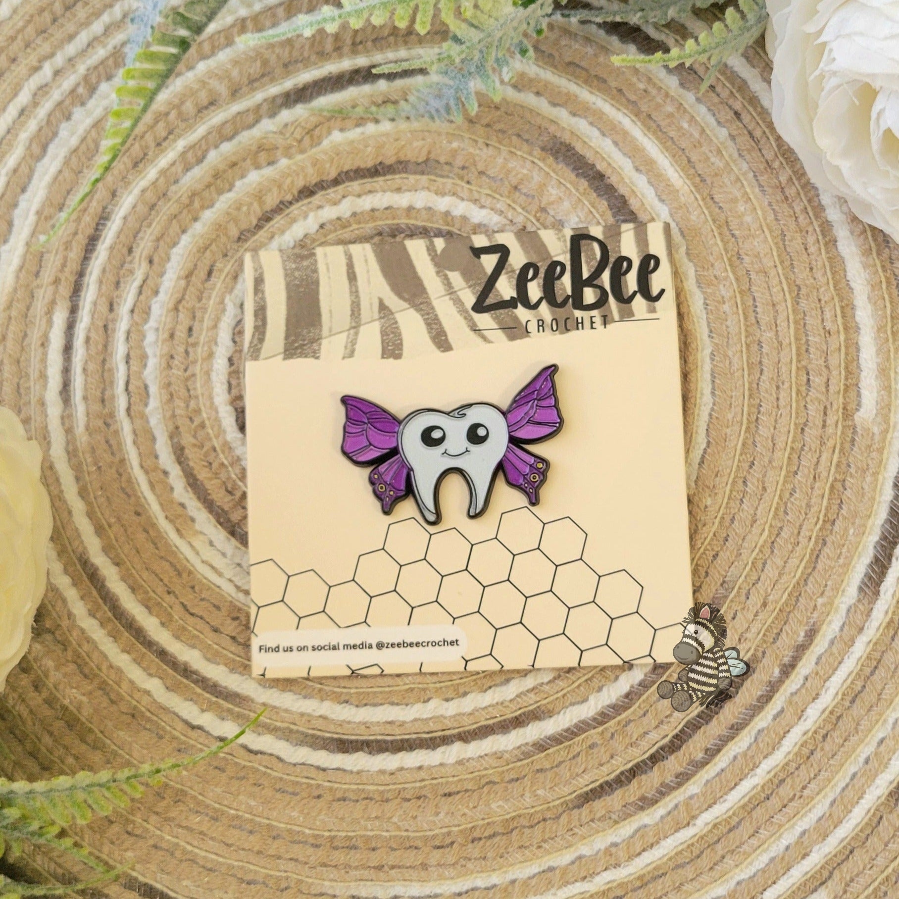 ZeeBee Crochet official tooth-fairy pin with purple wings on a wooden surface